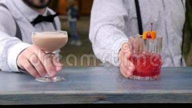 两<strong>名酒</strong>吧服务员端着酒，酒吧服务员在酒吧柜台上装饰着彩色饮料，手里拿着酒吧服务员冰镇饮料